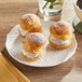 A Pavoni silicone baking mat with three cream puffs on a plate.