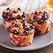 Three Pavoni big muffins with berries on a plate.