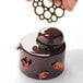 A hand holding a Pavoni Pavodecor circle chocolate.