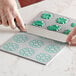 A person using a Pavoni Pavodecor circle silicone baking mold to cut out green icing.