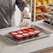 A person pouring batter into a Pavoni round silicone baking mold with 8 compartments.