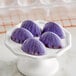 A white plate of Pavoni Praline egg-shaped chocolates with purple and white icing.