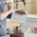 A woman using a Pavoni chocolate bar mold to pour chocolate.