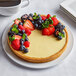 A tart made with a stainless steel micro-perforated tart ring with strawberries on top on a white plate.