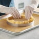 A person wearing gloves cutting a pie crust using a Pavoni stainless steel tart ring.