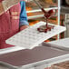 A person using a Pavoni Chocoflex chocolate mold to pour liquid chocolate onto a tray.