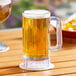 A Choice clear plastic beer mug filled with beer on a table outdoors.