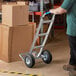 A man pushing a Lavex aluminum hand truck with a large box on top.