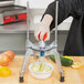 A person using a Vollrath Redco Wedgemaster to cut a cucumber.