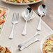 Acopa stainless steel serving utensils on a table with plates of food.