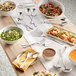 A table with bowls of food and Acopa stainless steel serving forks.