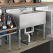 A Regency stainless steel underbar sink with a left drainboard and faucet on a counter.