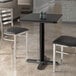 A Lancaster Table & Seating rectangular table with black wood finish and two chairs.