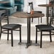 A wooden table with a dark walnut finish and two chairs in a restaurant dining area.