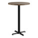 A Lancaster Table & Seating round table with a dark walnut finish and black metal base.