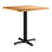 A Lancaster Table & Seating square table with a maple finish top and black base.