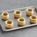 A tray of six White Toque small plantain cups on a baking sheet.