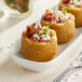 Three White Toque small plantain cups filled with food on a white plate.