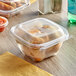 A plastic container with food and a dome lid on a table.