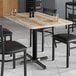A Lancaster Table & Seating rectangular table top with a barnwood finish on a table with black chairs and salt and pepper shakers.