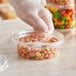 A hand picking up peanuts from an Inline Plastics Safe-T-Fresh deli container.