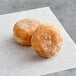 Two White Toque raspberry filled mini beignets on a white napkin.