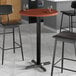 A Lancaster Table & Seating bar table with two black bar stools around it.