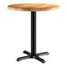 A Lancaster Table & Seating round wooden table with a black base.