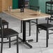 A Lancaster Table & Seating rectangular MDF table top with a gray wood finish on a table with black chairs.