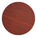 A Lancaster Table & Seating round wooden table top with a red mahogany finish.