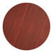 A Lancaster Table & Seating round wood table top with a red mahogany finish.