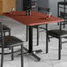 A Lancaster Table & Seating rectangular table top with a red mahogany finish on a table with chairs around it.