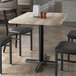 A rectangular table with a gray wood finish and a black metal base, surrounded by black chairs.