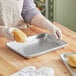 A person wearing gloves using a Nordic Ware quarter size bun pan to hold a loaf of bread.