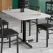 A Lancaster Table & Seating rectangular MDF table top with a white marble finish on a table with black chairs and glasses.