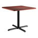 A Lancaster Table & Seating square table with a black base and red mahogany top.