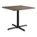 A Lancaster Table & Seating square table with a dark walnut top and black base.