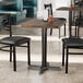 A Lancaster Table & Seating rectangular table with a dark walnut finish and two chairs in a restaurant.