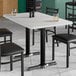 A white rectangular table with a white marble finish and black chairs.