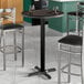 A Lancaster Table & Seating round bar height table with black wood finish and a black pole with a black top.