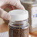 A hand holding a white 63/485 Polypropylene Spice Cap.