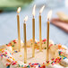 A white birthday cake with Wilton metallic gold candles on top.