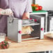 A woman using an Estella manual turnover machine to make a pastry.