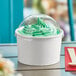 A white Choice frozen yogurt cup with a clear dome lid on a table.