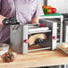 A person in black gloves using the Estella Manual Turnover Machine to make a pastry.
