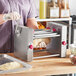 A woman using an Estella manual turnover machine on a counter.