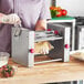 A woman using an Estella semi-circle die in a machine to make food.