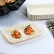 A Fineline ivory plastic snack tray with food on it next to a fork.