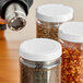 A person using a hot air gun to shrink a clear band around a jar with seeds.