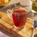 A glass mug of Caribou Coffee on a wooden board.